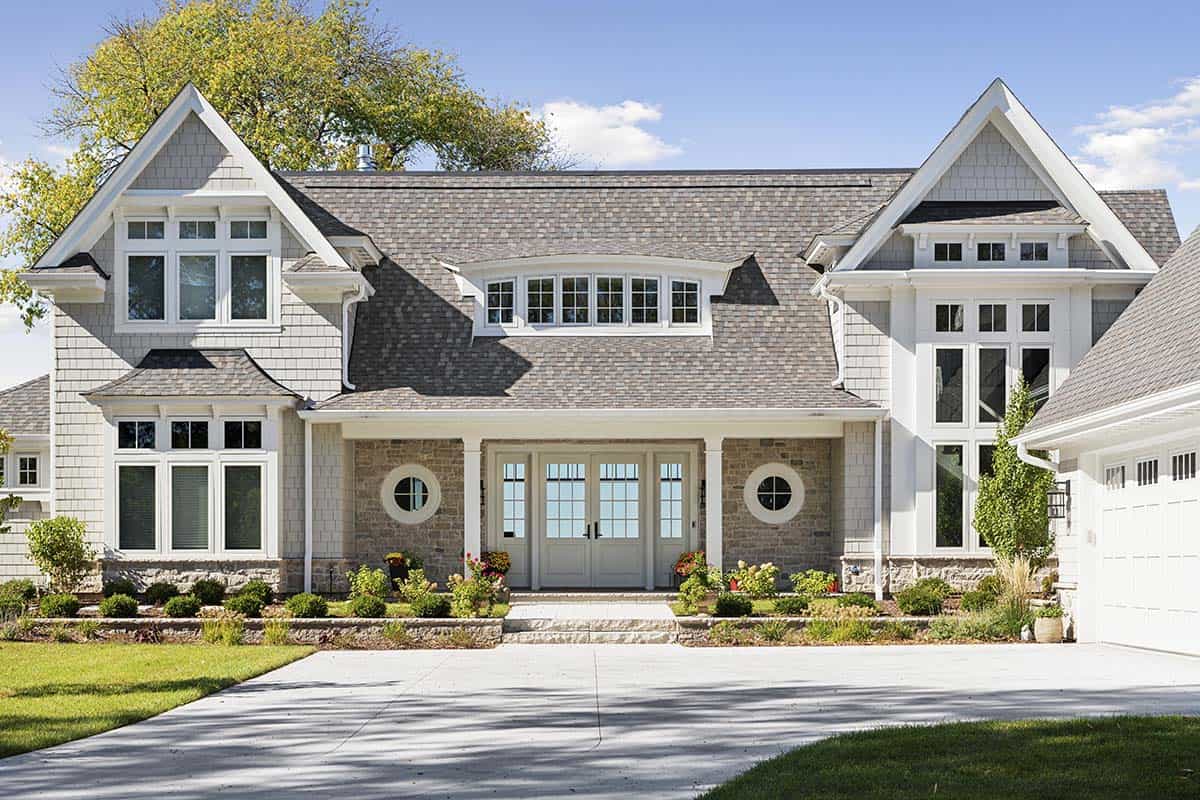 Front facade with covered porch, round windows, and double entry doors