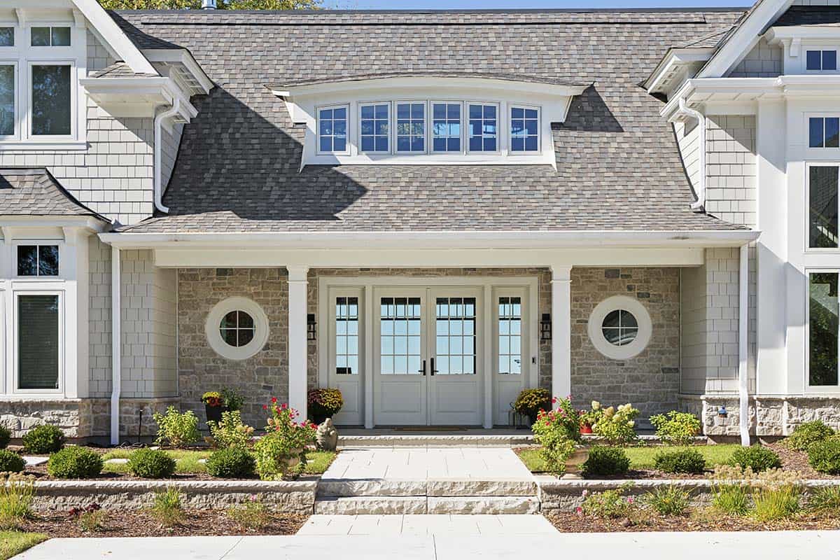 Close-up of covered entry porch with stone columns and round windows