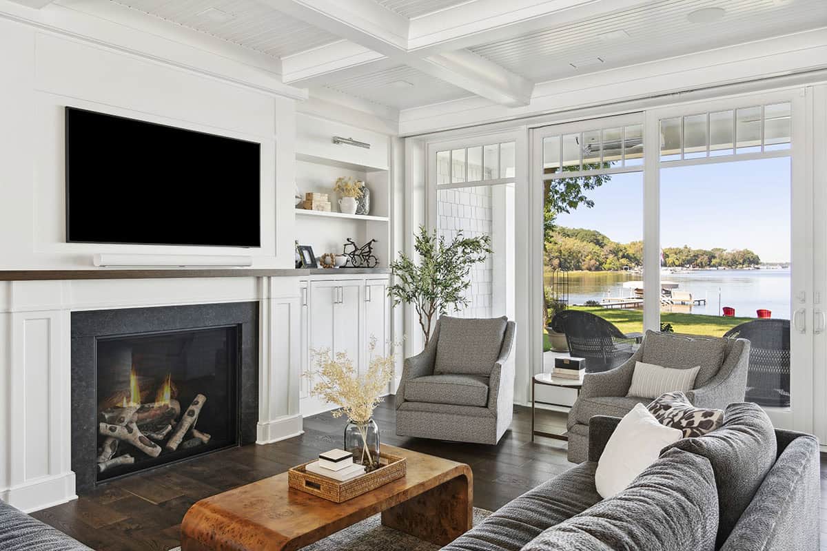 Living room with stone fireplace and mounted TV facing lake