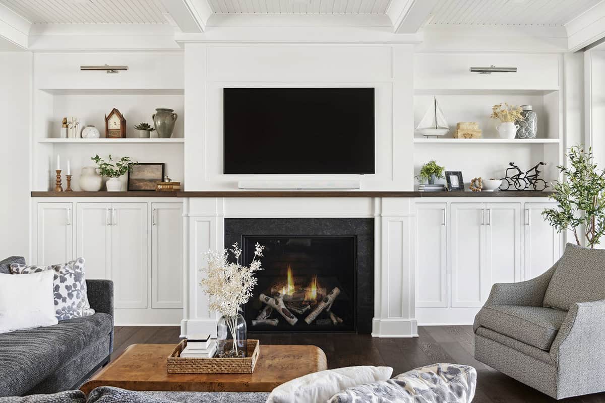 Fireplace wall with built-in shelving and wood mantel