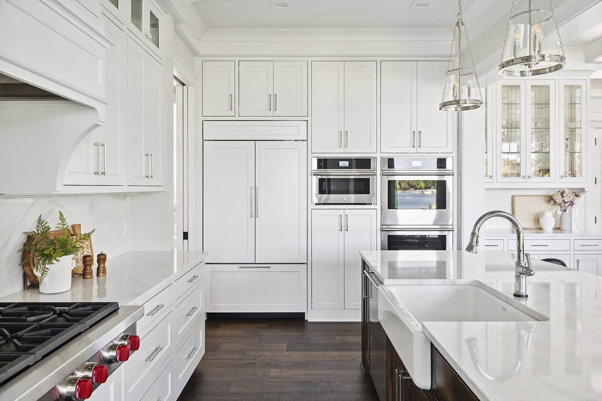 Kitchen wall with paneled refrigerator, double ovens, and pendant lights