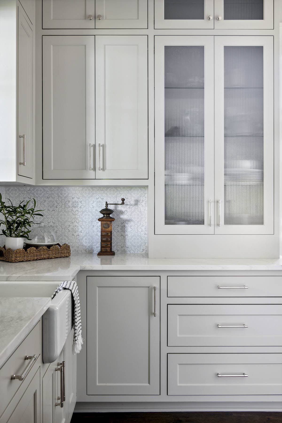Close-up of ribbed glass cabinet doors and patterned tile backsplash