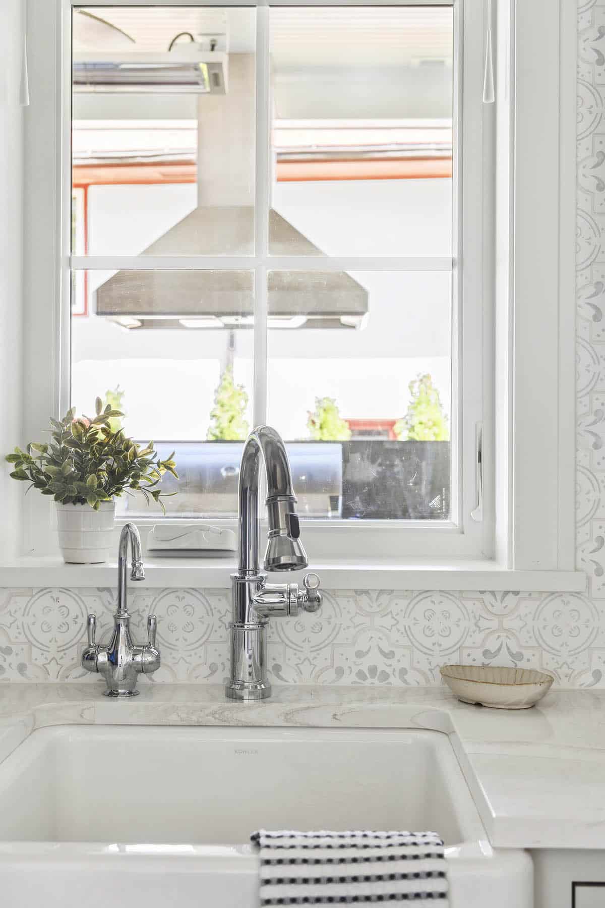 Farmhouse sink faucet detail with patterned tile backsplash