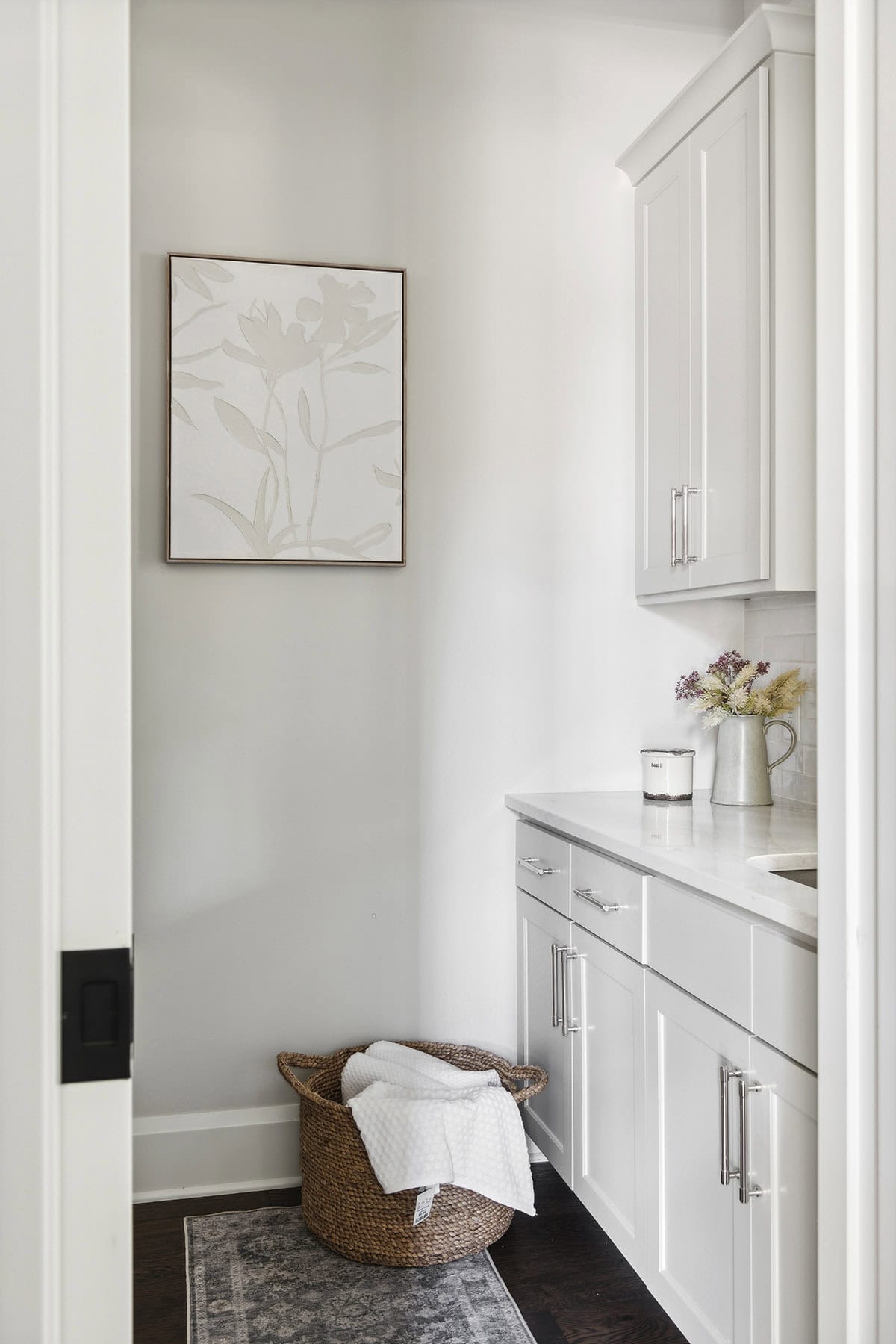 Laundry room nook with woven basket and floral wall art
