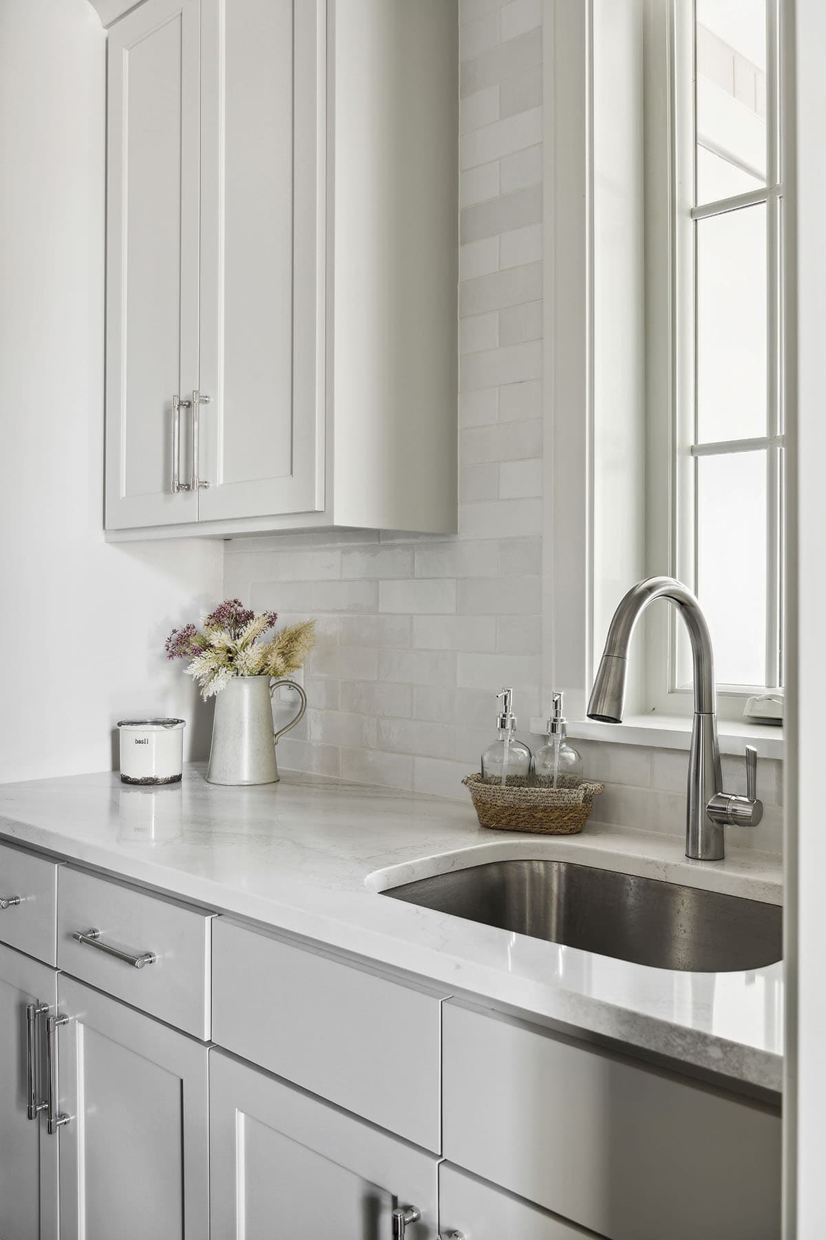 Laundry sink with subway tile backsplash and soap dispensers