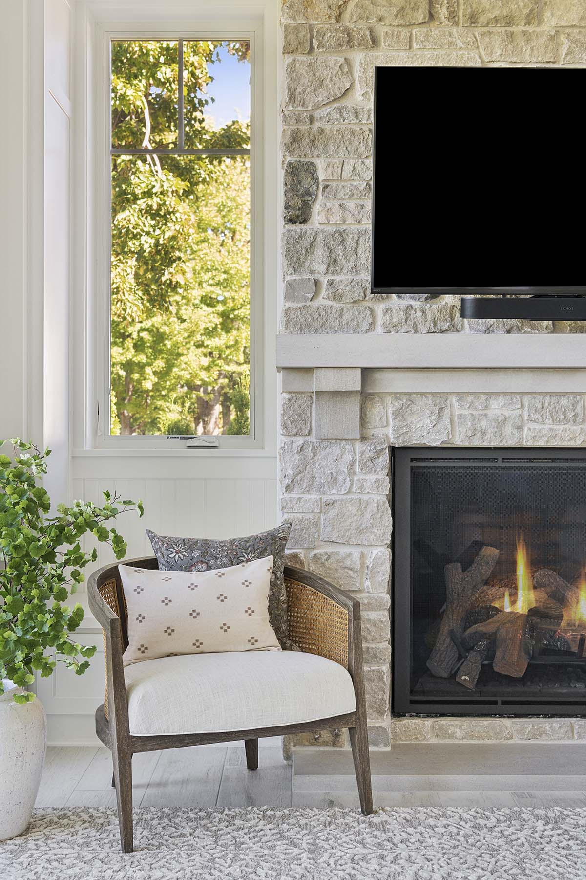 Close-up of stone fireplace with gas logs and cane accent chair