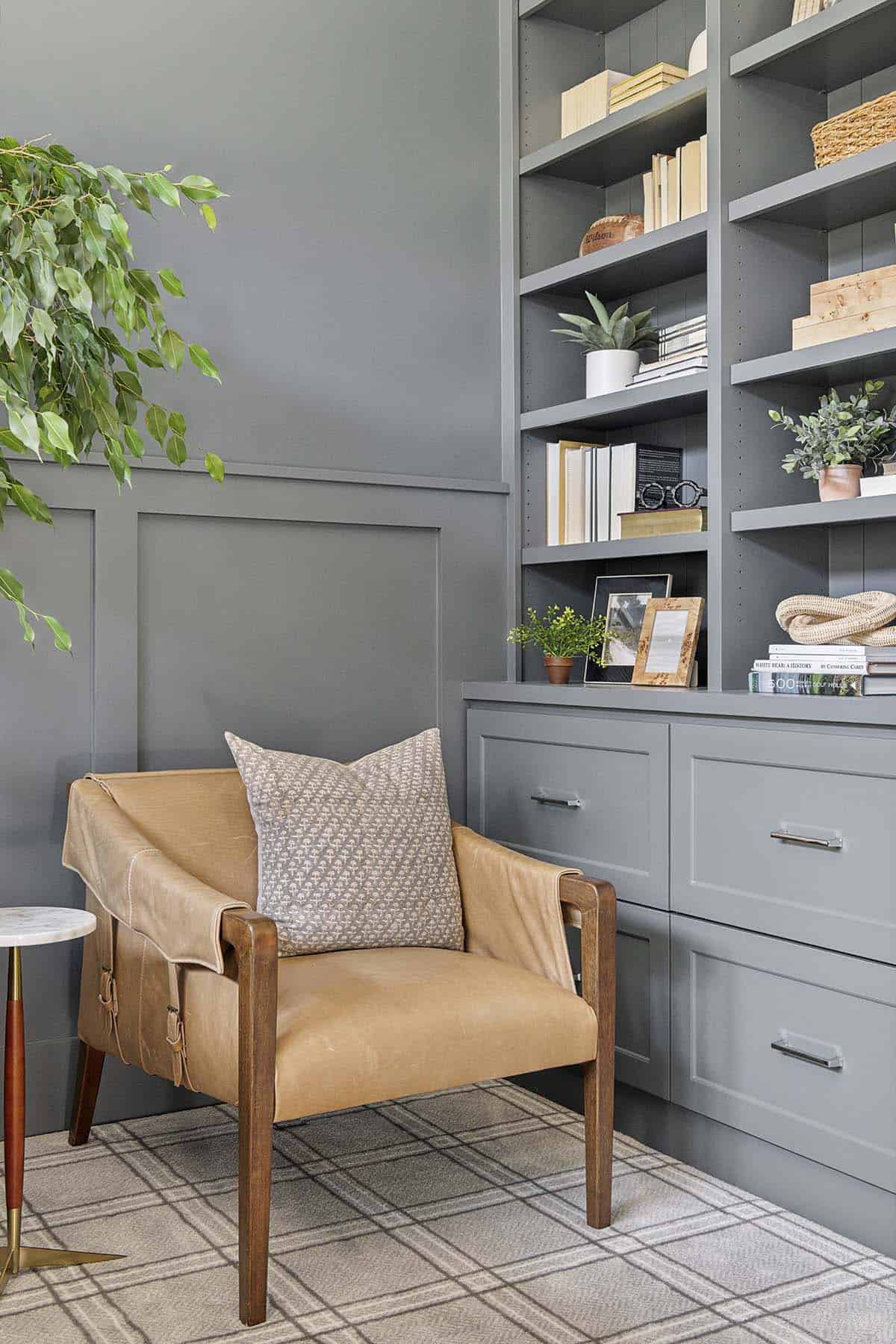 Leather armchair beside gray built-in shelving in study