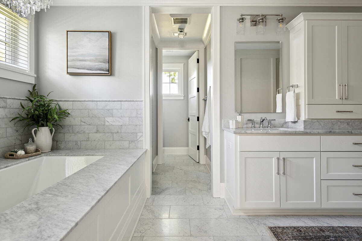 Primary bathroom with soaking tub, marble tile, and vanity