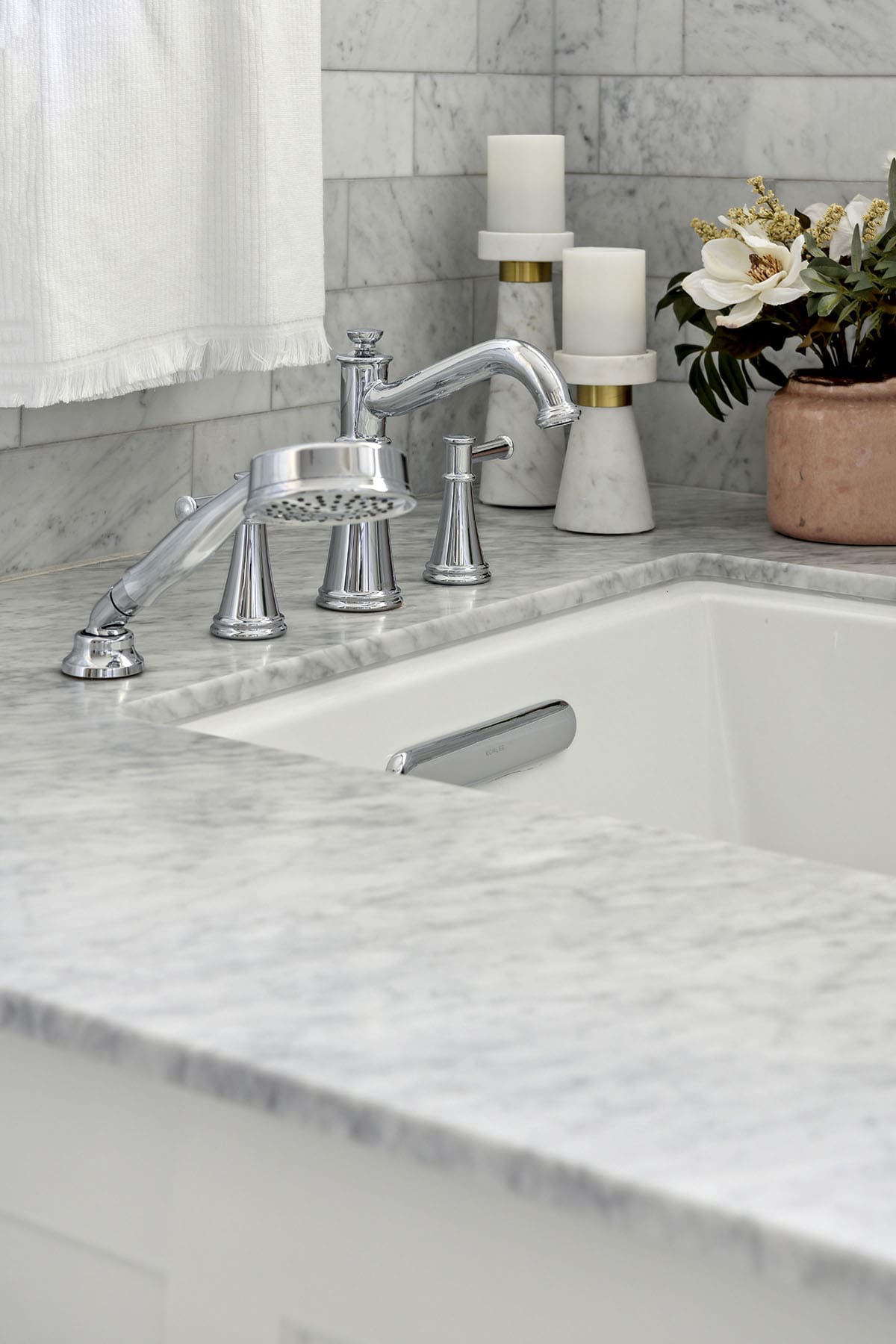 Close-up of tub faucet with candles and floral accent