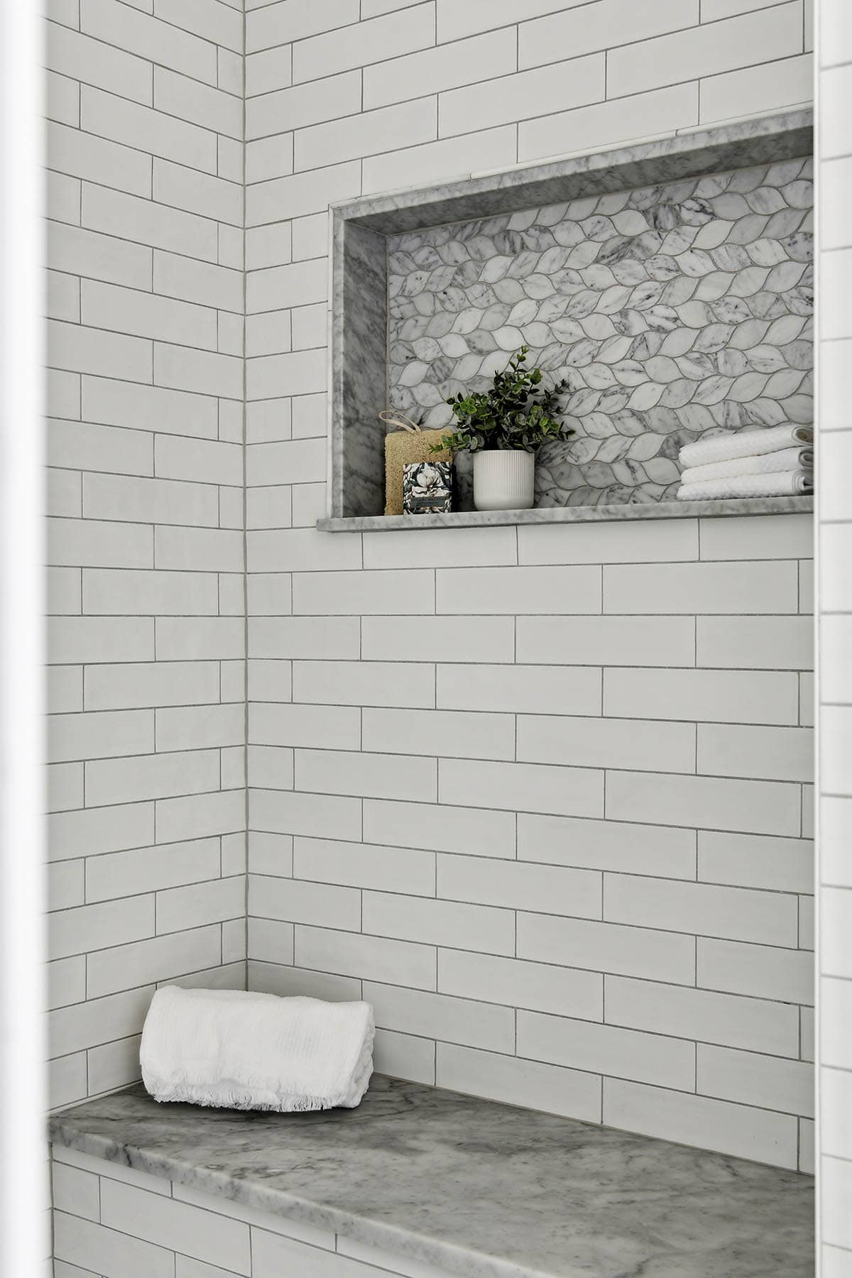 Shower tile detail with marble mosaic niche and towels