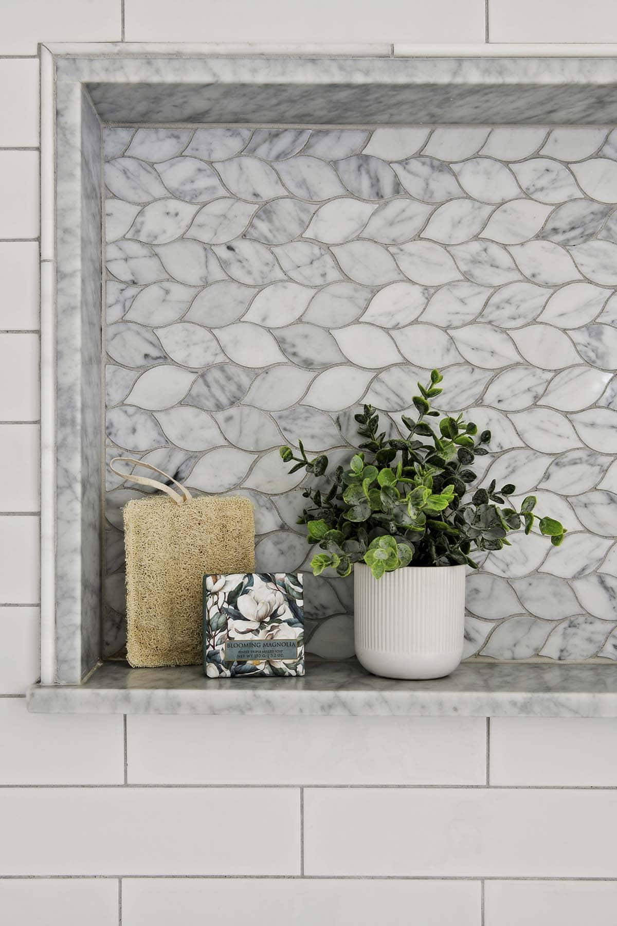 Close-up of marble leaf-pattern tile niche with plant