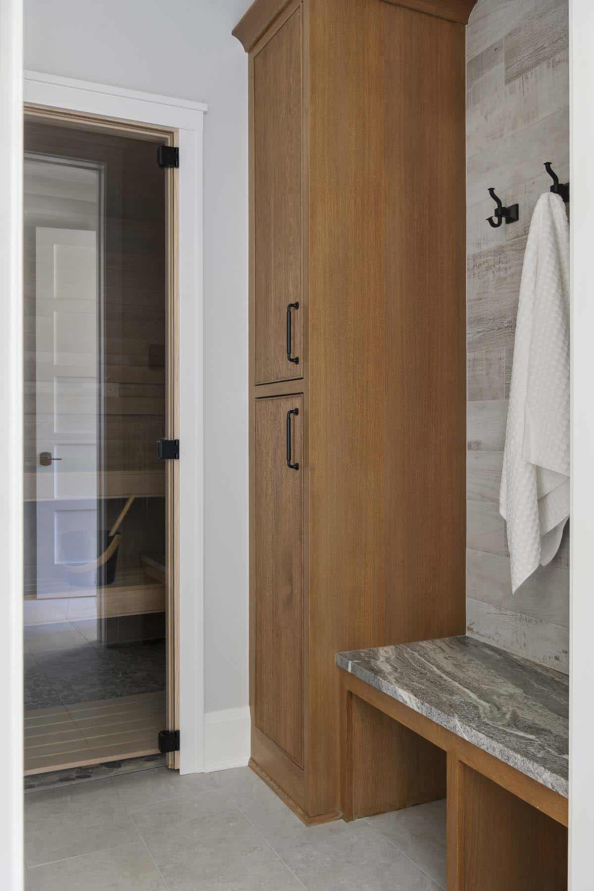 Wood-paneled sauna entrance next to marble-topped locker bench