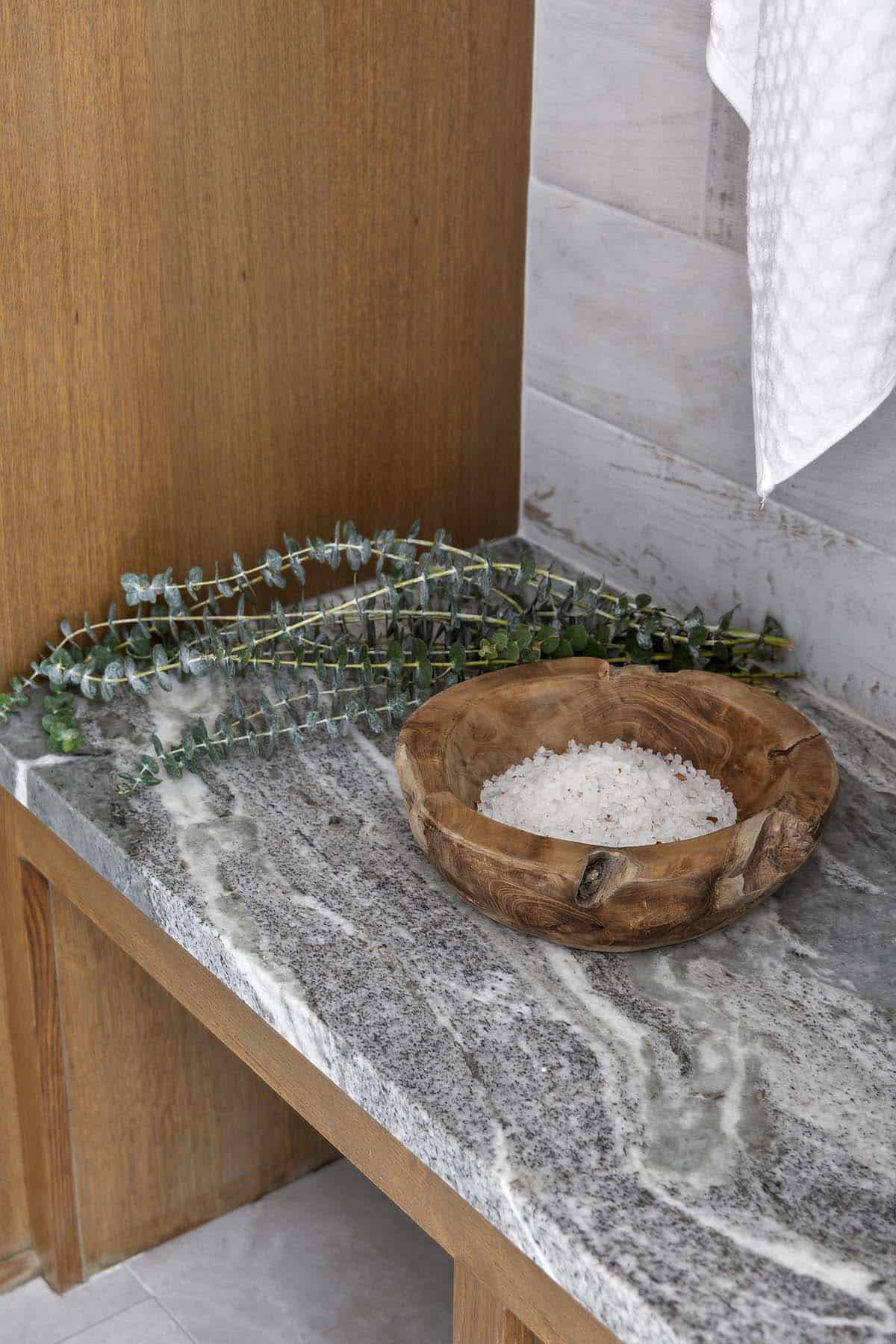 Wooden bowl with sea salt on stone bench in spa area