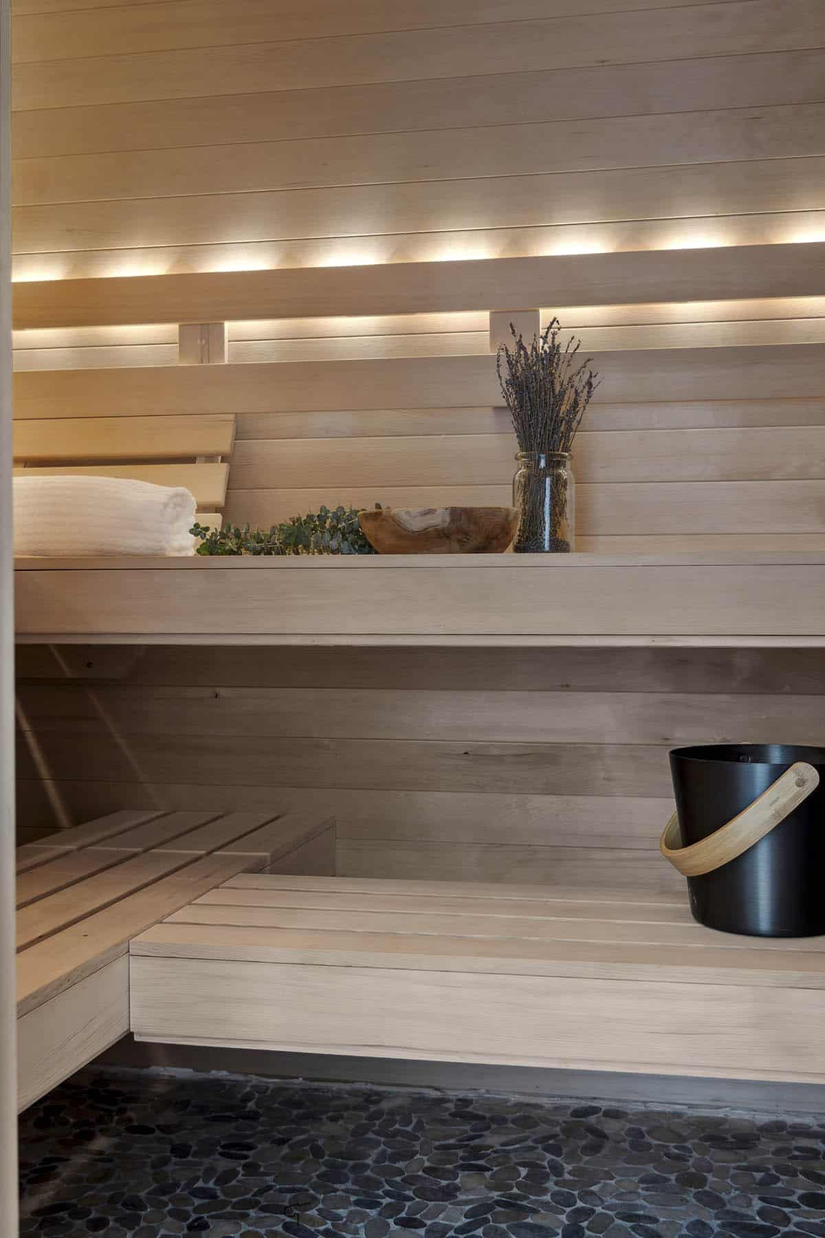 Close-up of lit sauna benches with lavender and bucket