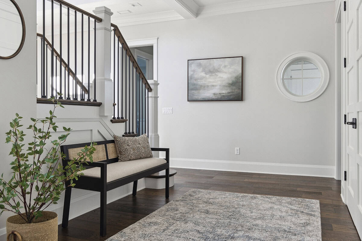 Foyer bench beneath staircase with round window and art