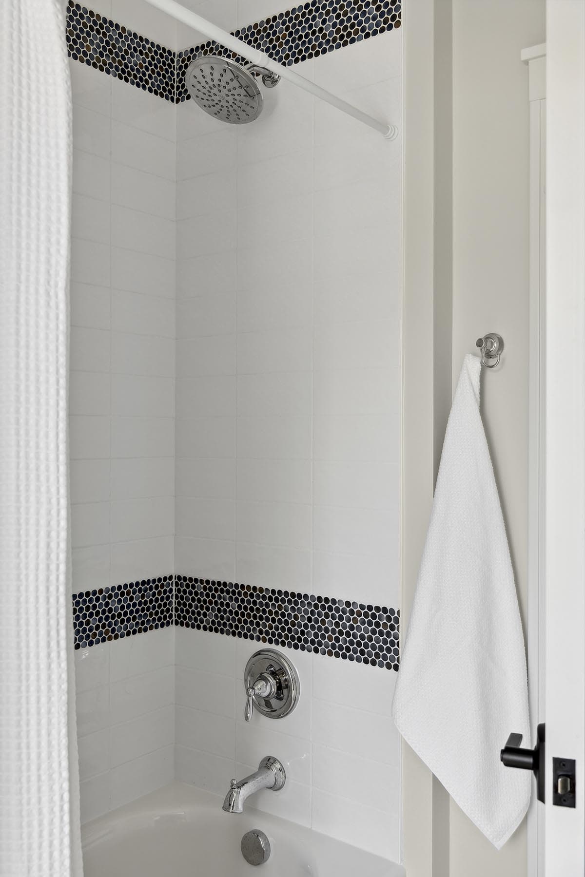 Tub-shower combo with black penny tile accent band
