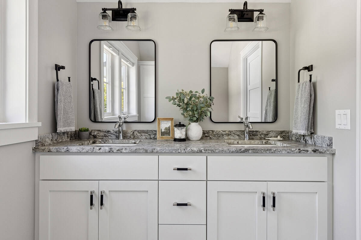 White double vanity with granite counter and round mirrors