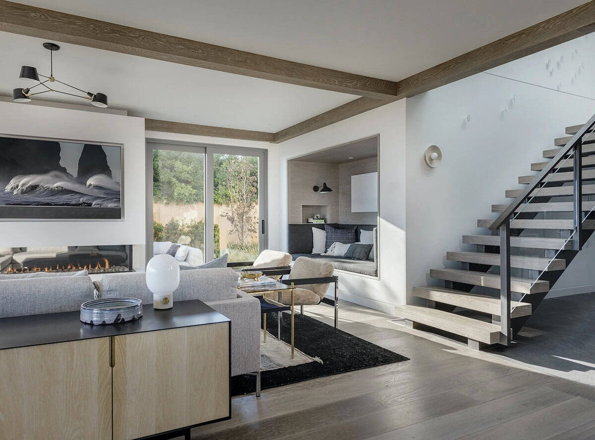 Living room with gray sofas, wall-mounted fireplace, built-in window nook seating, and a floating wood-and-steel staircase