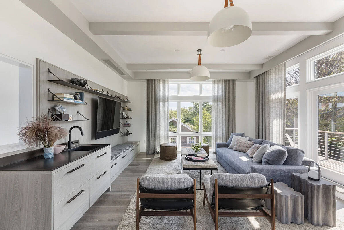 Family room with wood beam ceiling, gray sectional sofa, built-in shelving with wall-mounted TV, and glass balcony doors