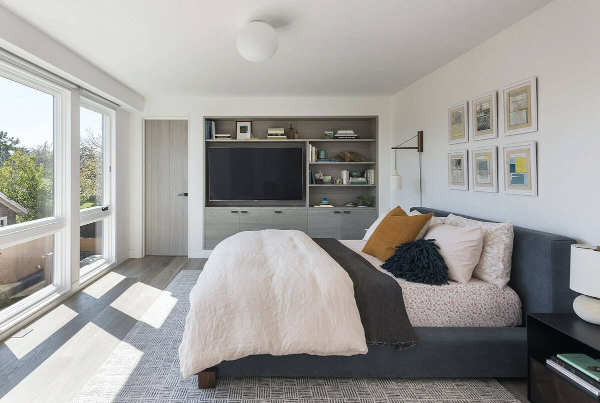 Bedroom with dark upholstered daybed, gray built-in media cabinet, patterned pillows, and framed art gallery wall