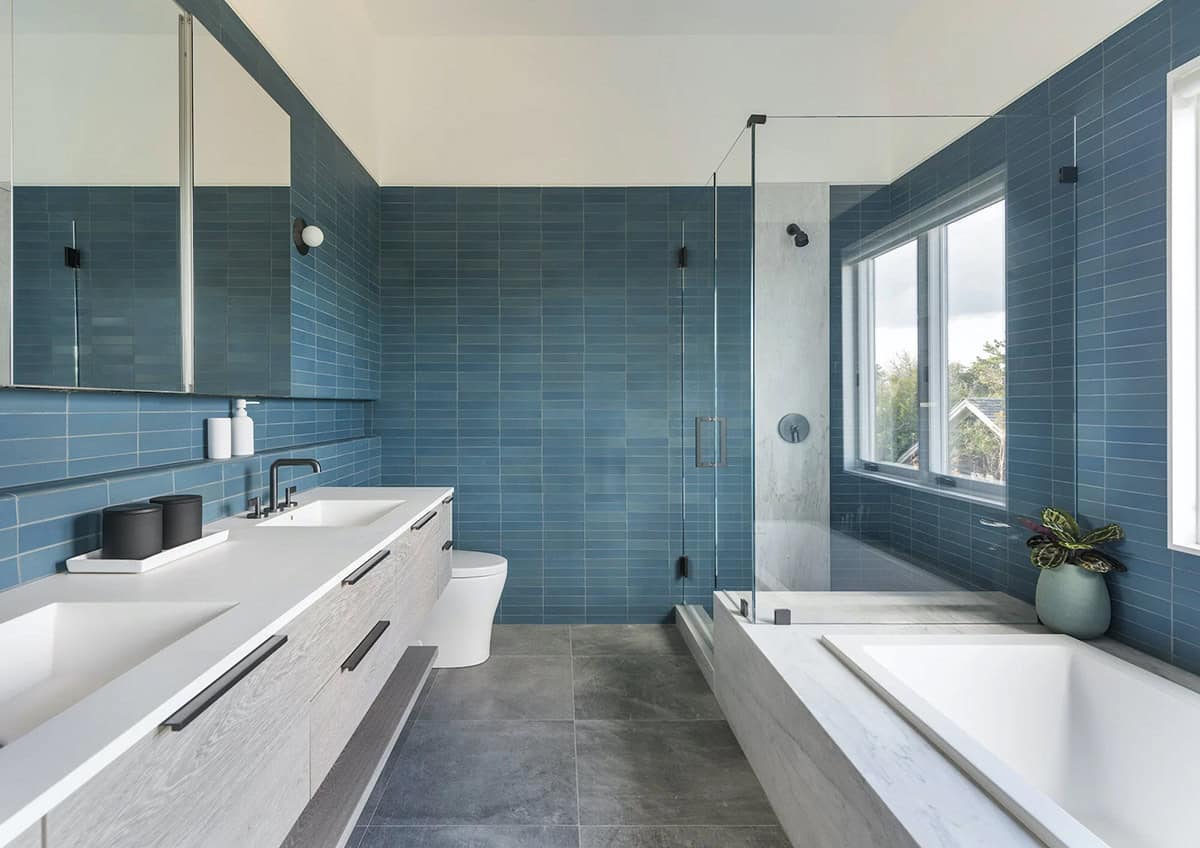 Bathroom with blue subway tile, floating double vanity, glass shower enclosure, and soaking tub by a window