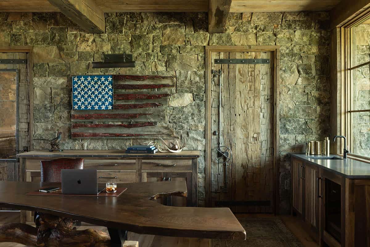 Rustic stone office with live-edge desk, weathered barn door, and handmade American flag wall art