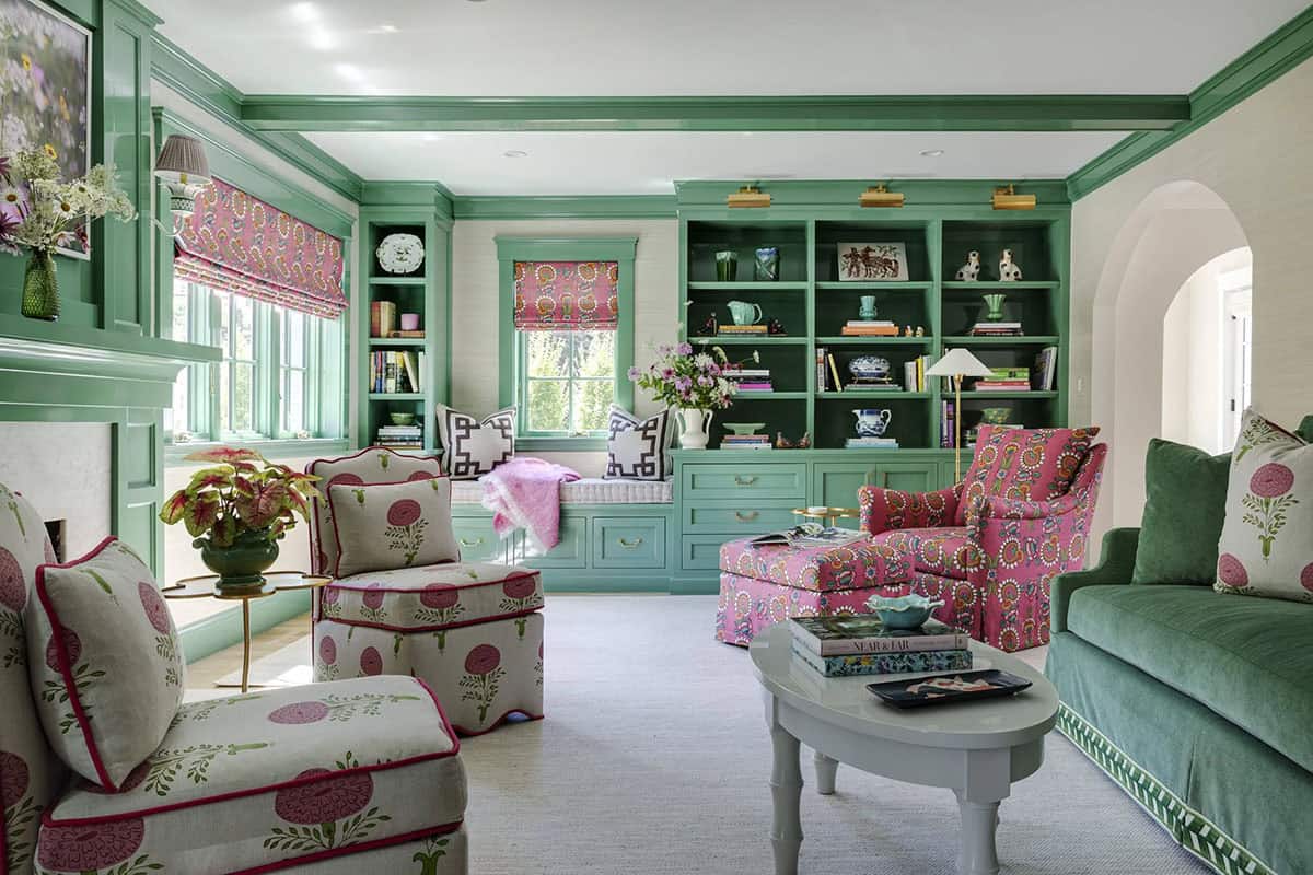 Green-paneled sitting room with pink floral armchairs, a green sofa, and built-in bookshelves