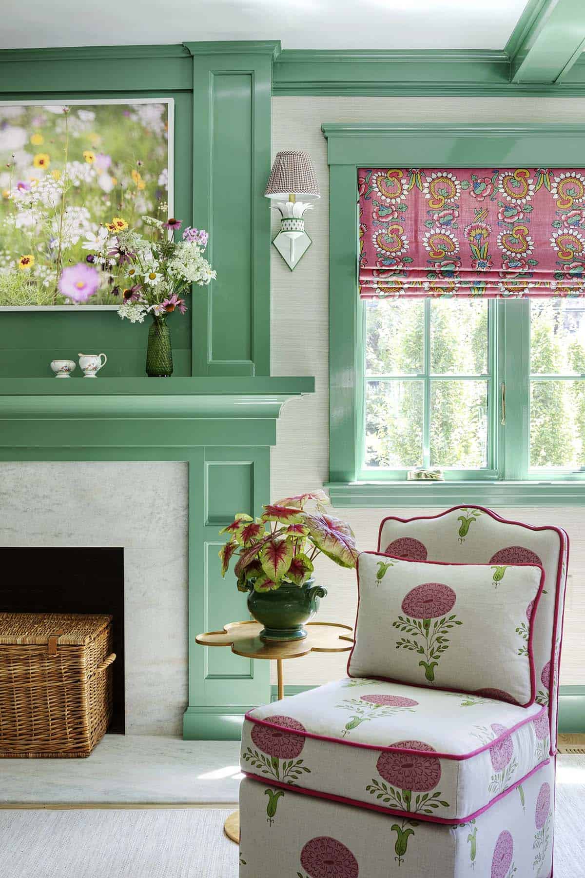 Green marble fireplace with mantel decor, potted caladium, and a pink floral slipper chair