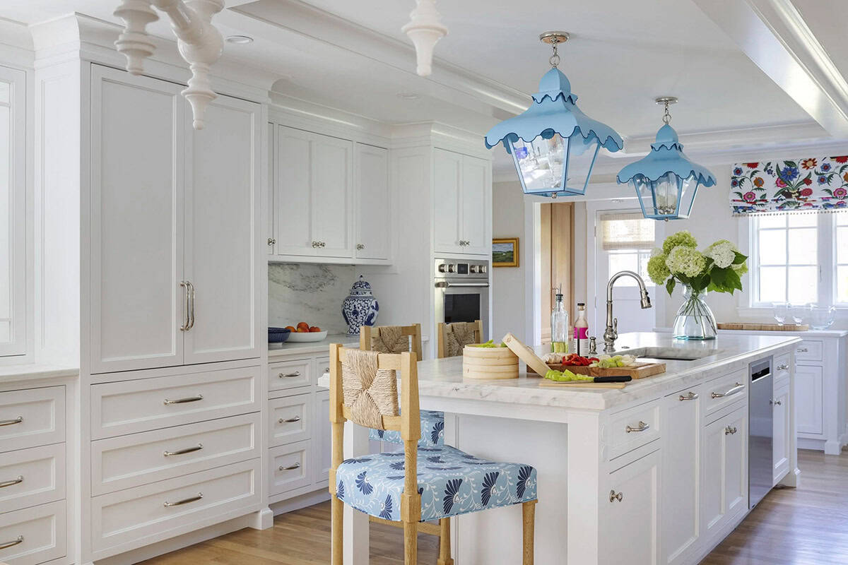 Wide view of white kitchen with scalloped blue pendant lights and blue-and-white floral roman shade