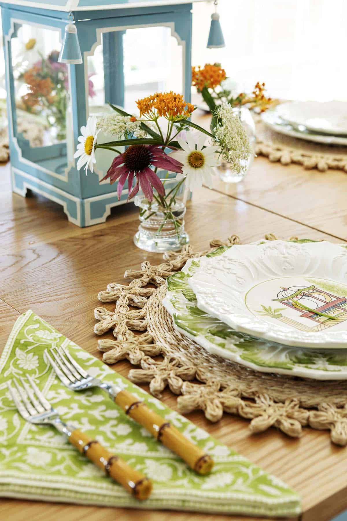 Table setting with scalloped green plates, wildflowers, and bamboo-handled flatware