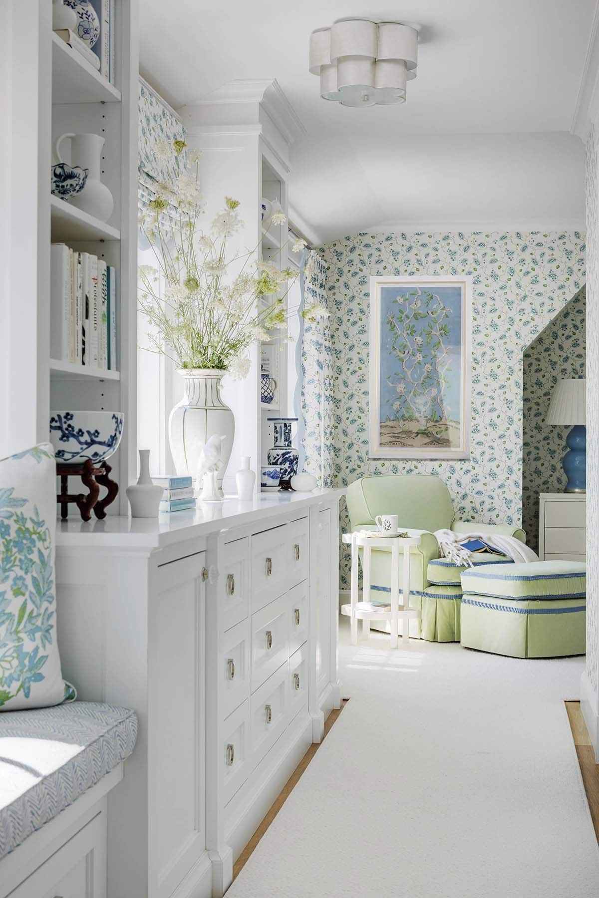 Hallway with white built-in cabinetry, blue-and-white china, and a green armchair reading nook