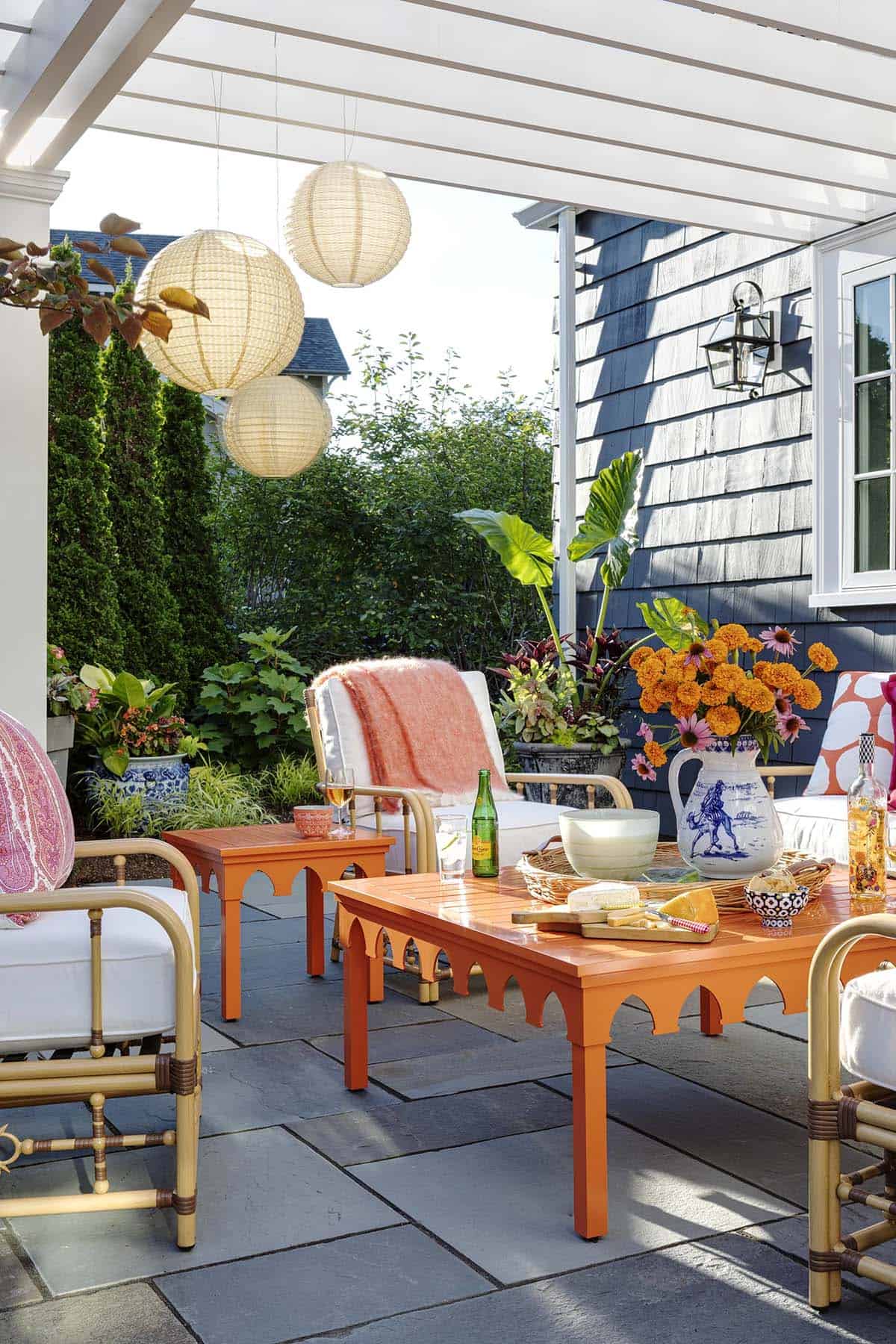 Close-up of orange arched coffee table on patio with cheese board and paper lanterns overhead