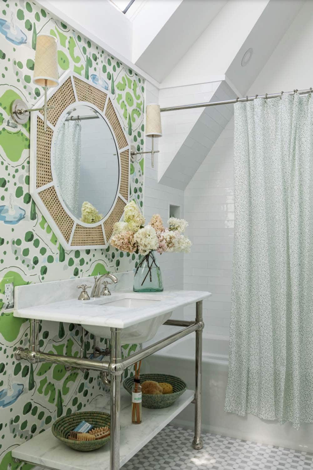 Skylit green-and-white bathroom with cane-framed mirror, console sink, and dotted shower curtain
