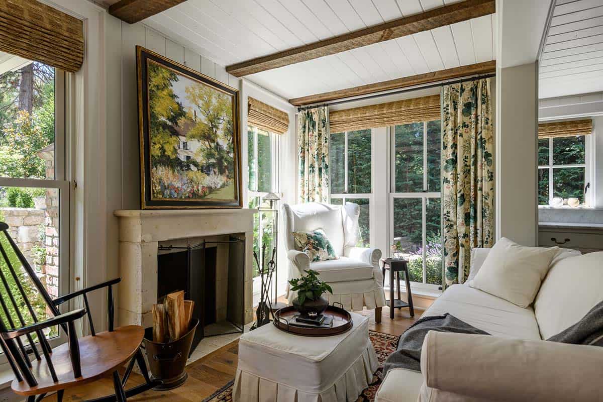 Cozy living room with stone fireplace, white slipcovered furniture, and floral curtains
