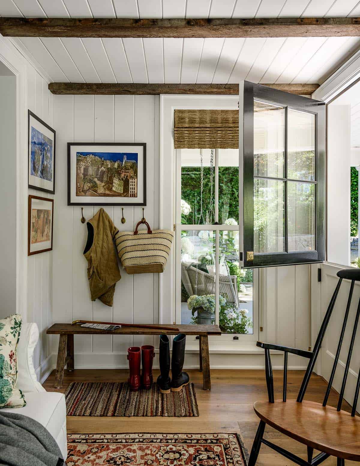 Mudroom with Dutch door, wall hooks, boot bench, and layered rugs