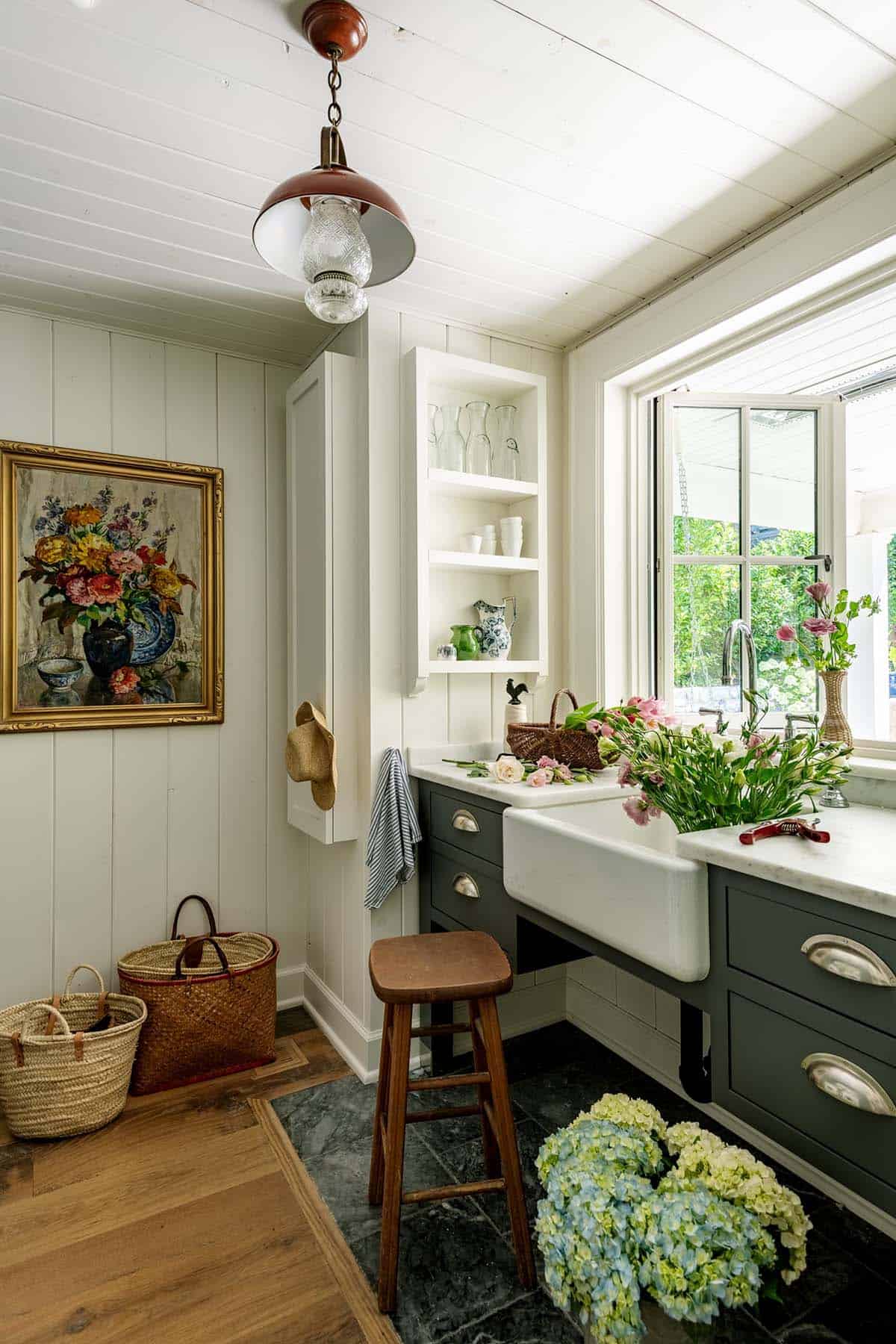 Butler's pantry with farmhouse sink, dark green cabinetry, and fresh cut flowers