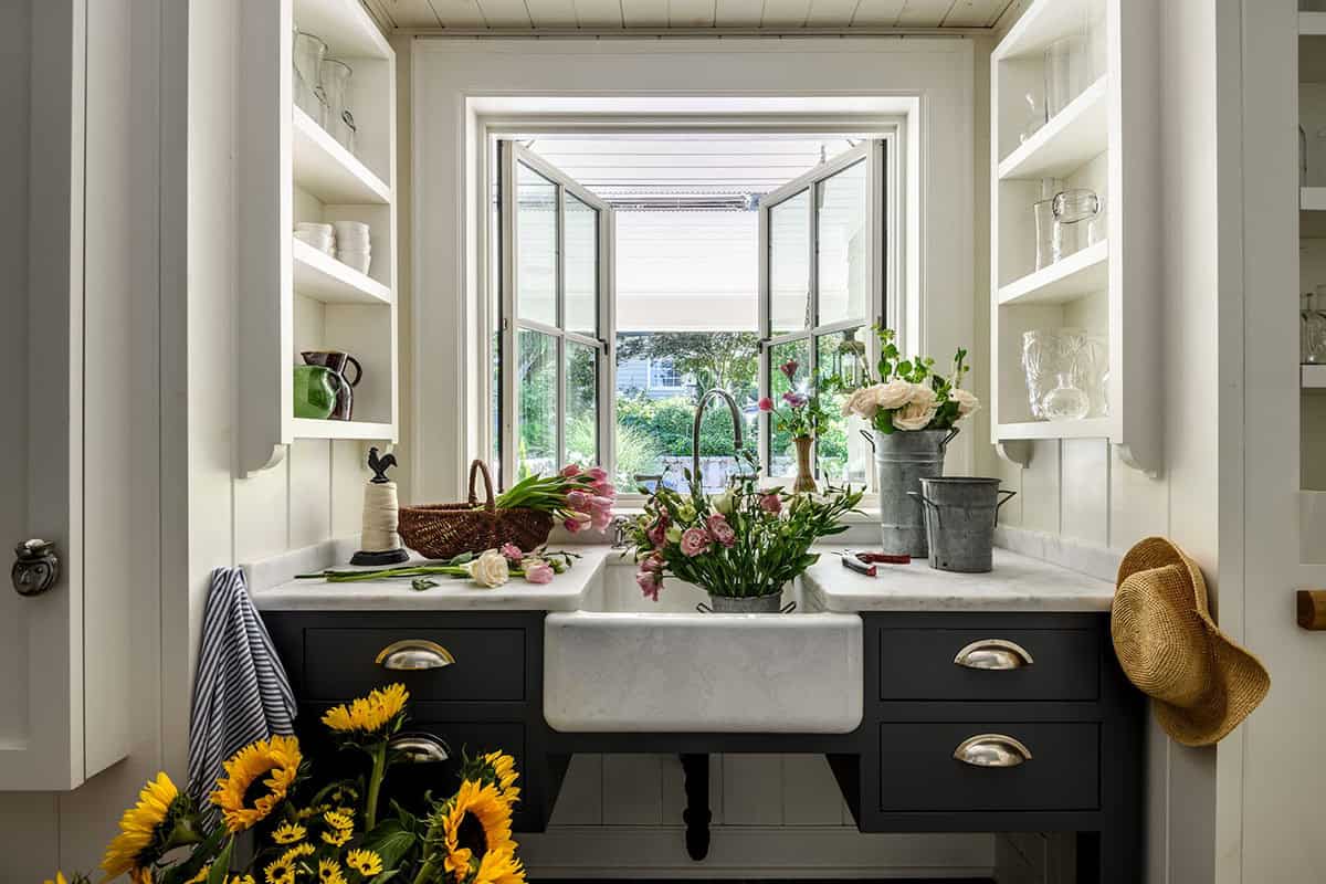 Flower-arranging station with marble counters and casement windows overlooking garden
