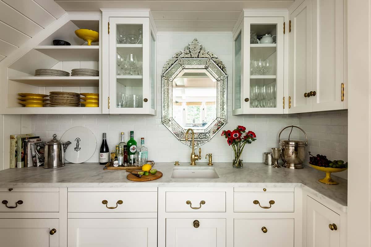 Wet bar with Venetian mirror, brass fixtures, and glass-front cabinets