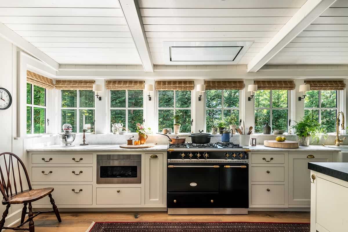 Kitchen with black range, brass hardware, and wall of garden-view windows