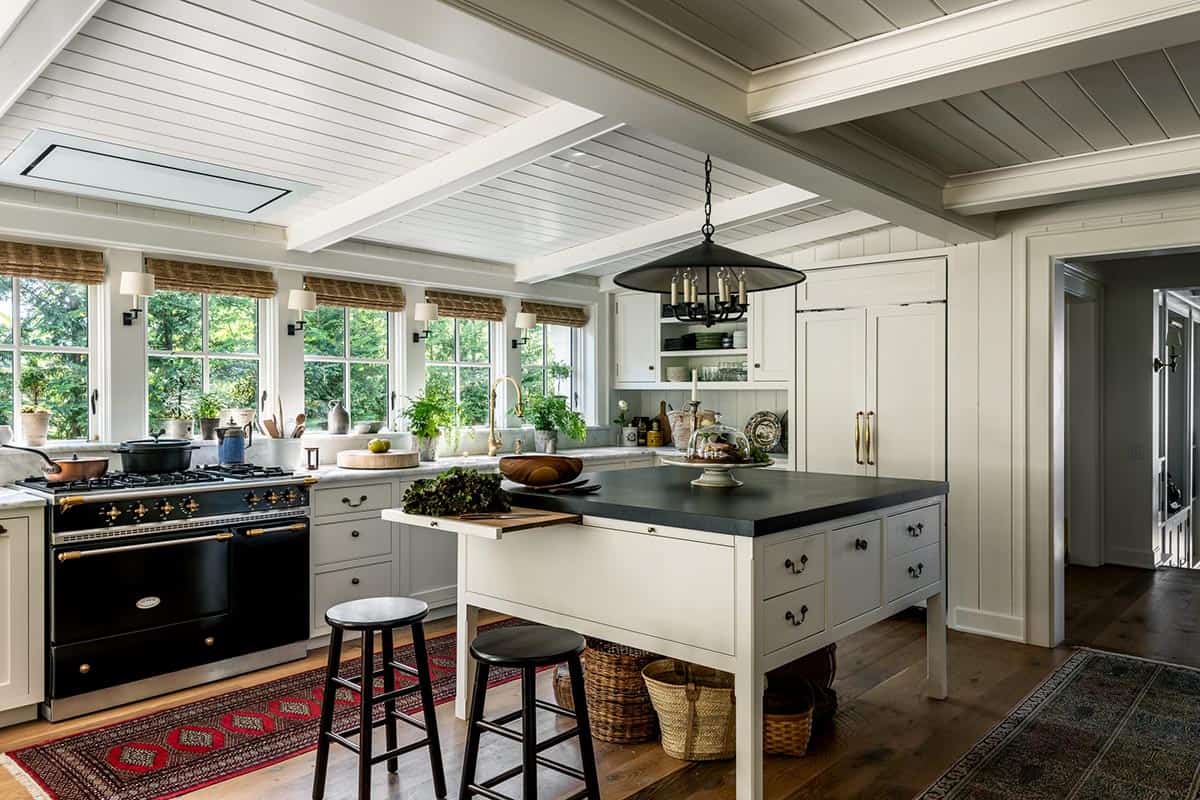 Kitchen island with soapstone counter beneath beamed ceiling