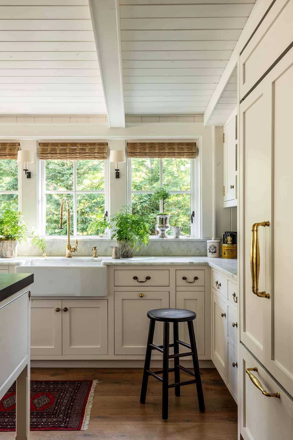 Kitchen corner with farmhouse sink, brass faucet, and built-in cabinetry