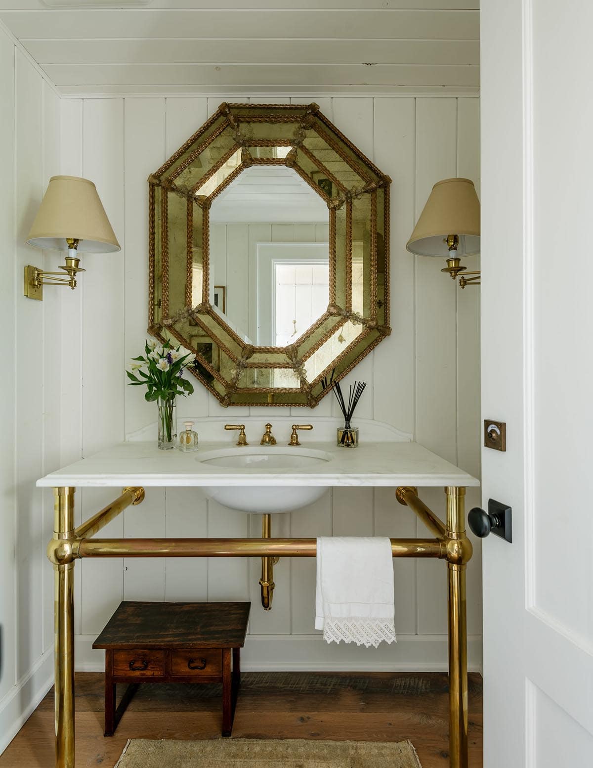 Powder room with brass console sink and ornate gold mirror