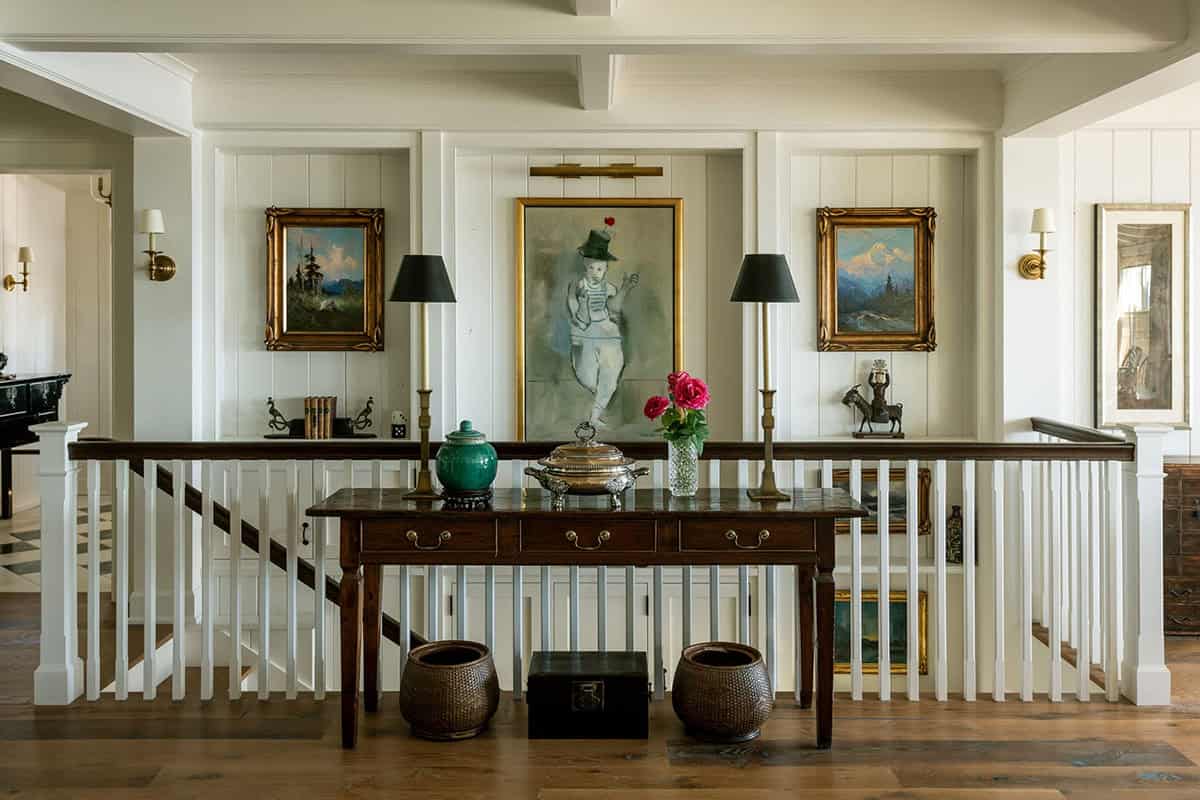 Staircase landing with console table, framed art, and sconces