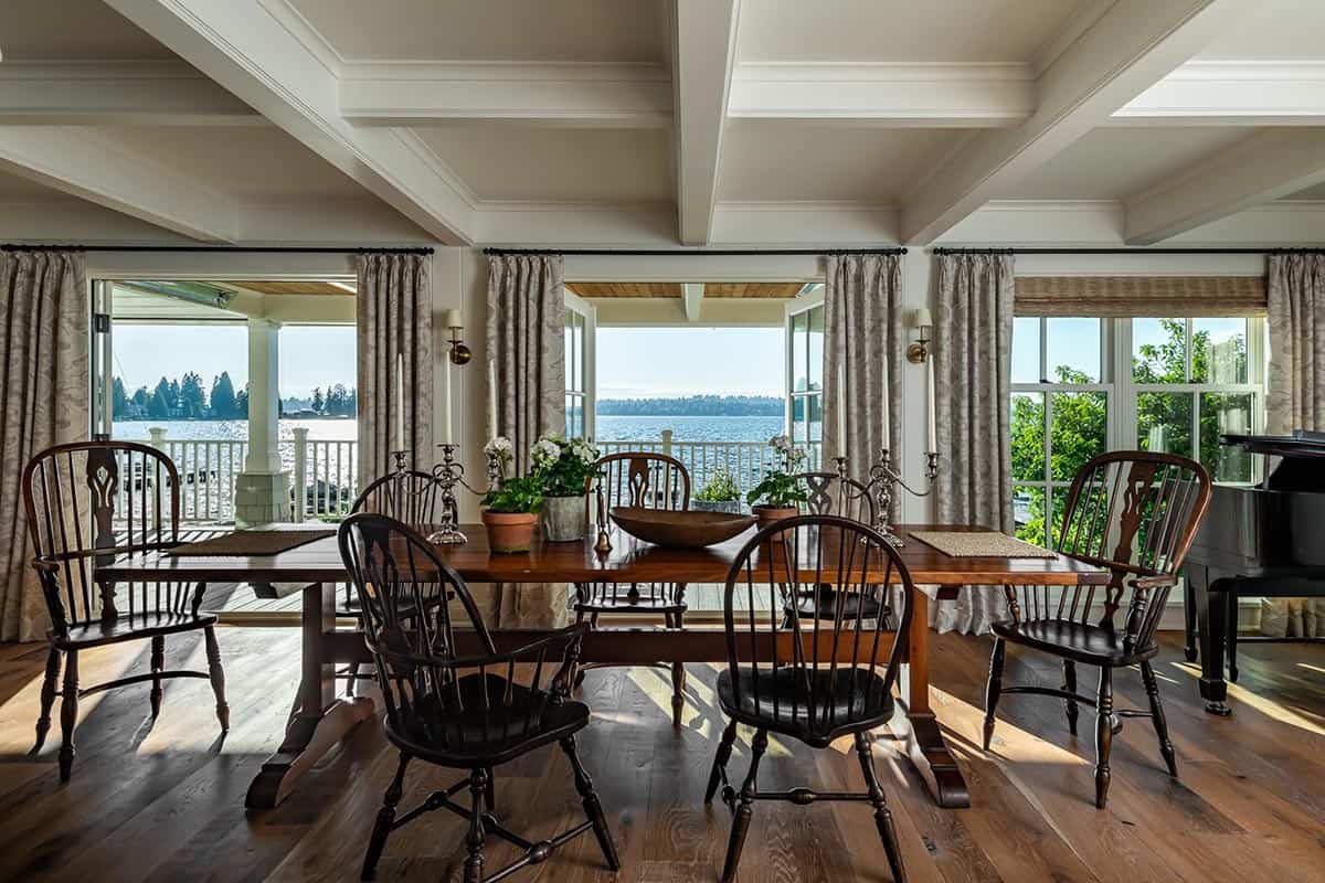 Dining room with wood table, Windsor chairs, and lake view through open doors