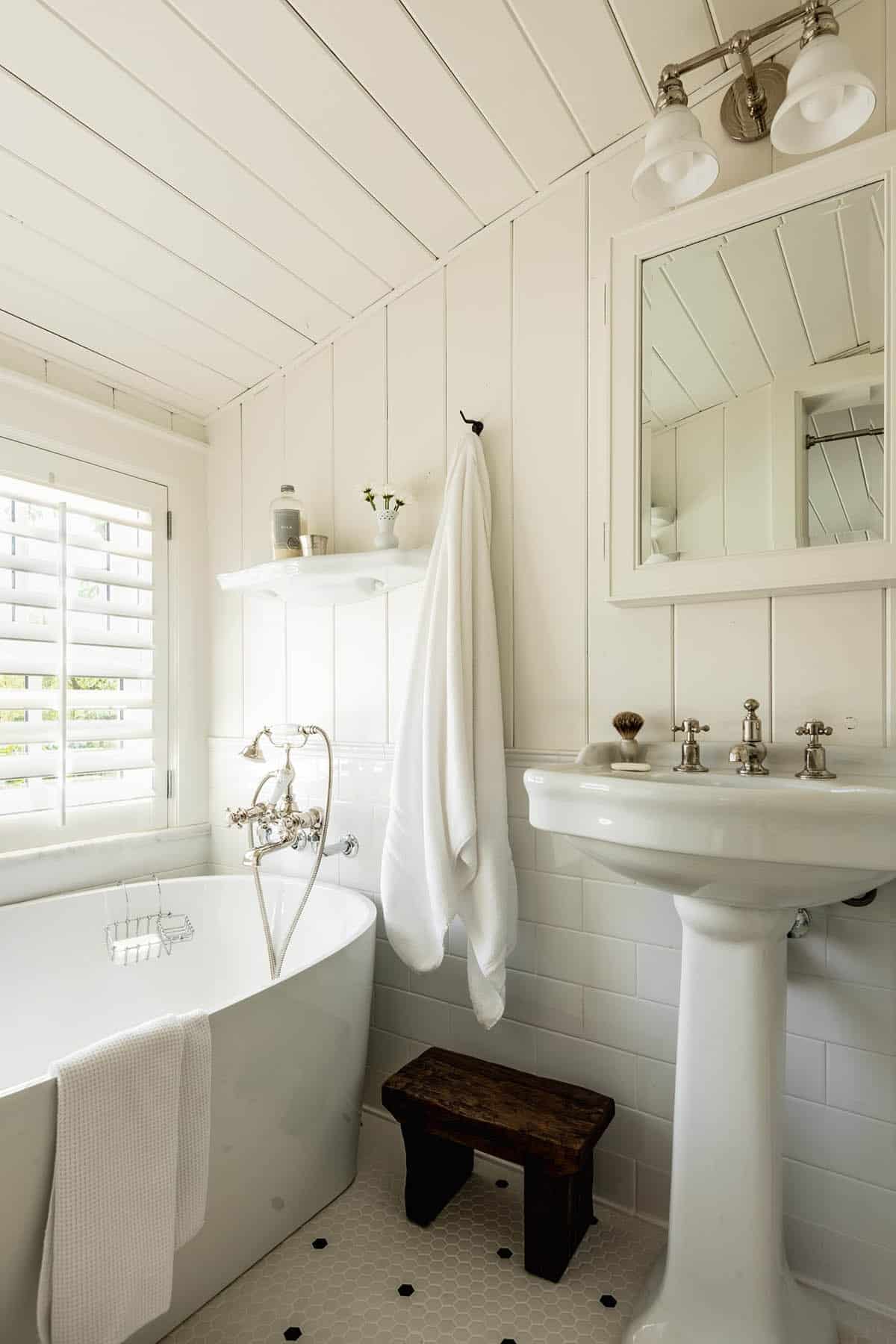 White bathroom with freestanding tub, pedestal sink, and hexagon tile floor