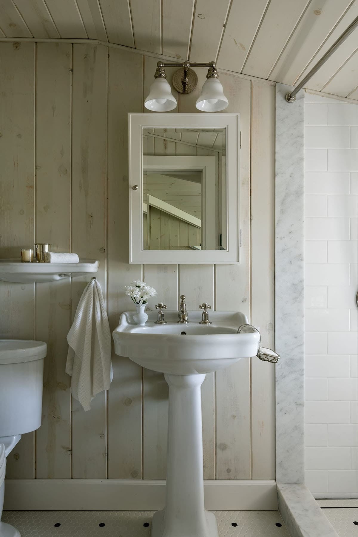 Shiplap bathroom with pedestal sink, medicine cabinet, and marble shower surround