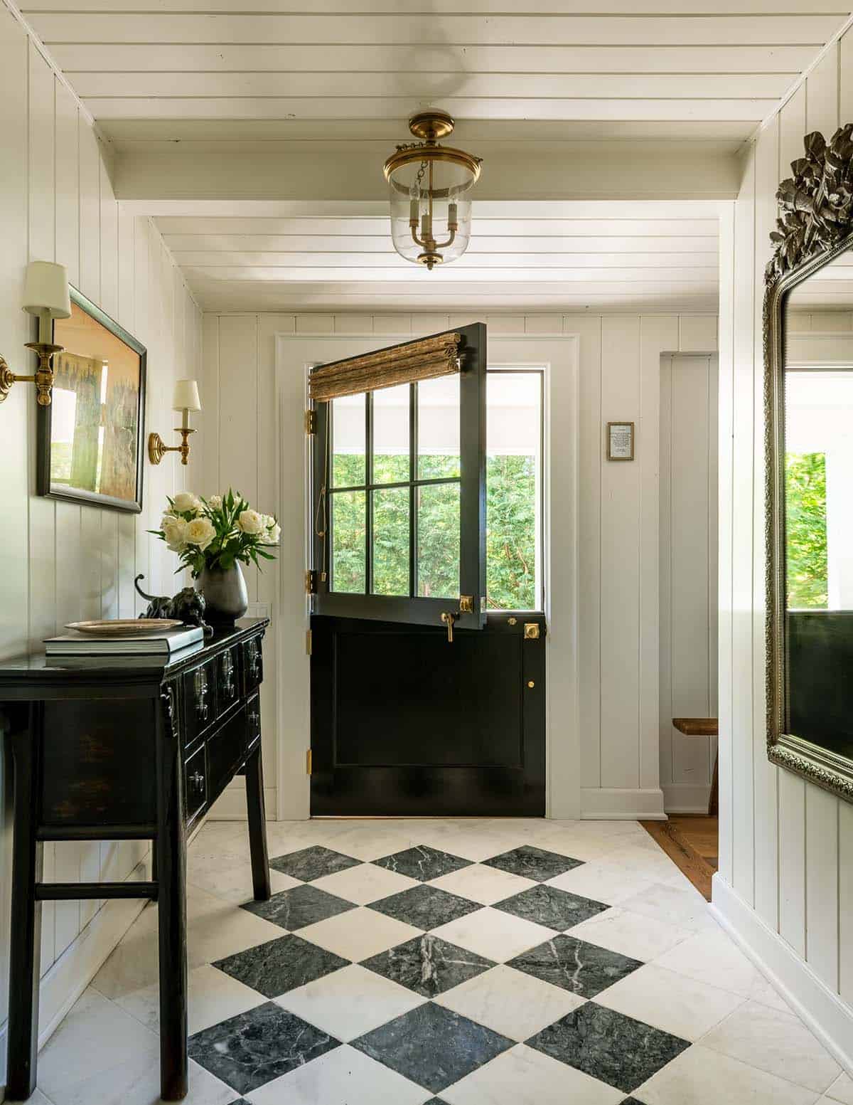 Entry hall with black Dutch door, marble checkerboard floor, and ornate mirror