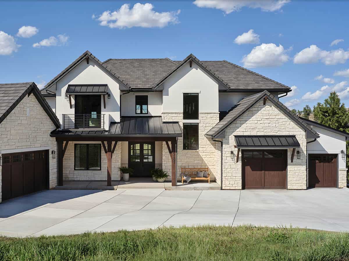 Two-story transitional mountain home exterior with stone and stucco siding, dark metal roof, and covered entry porch