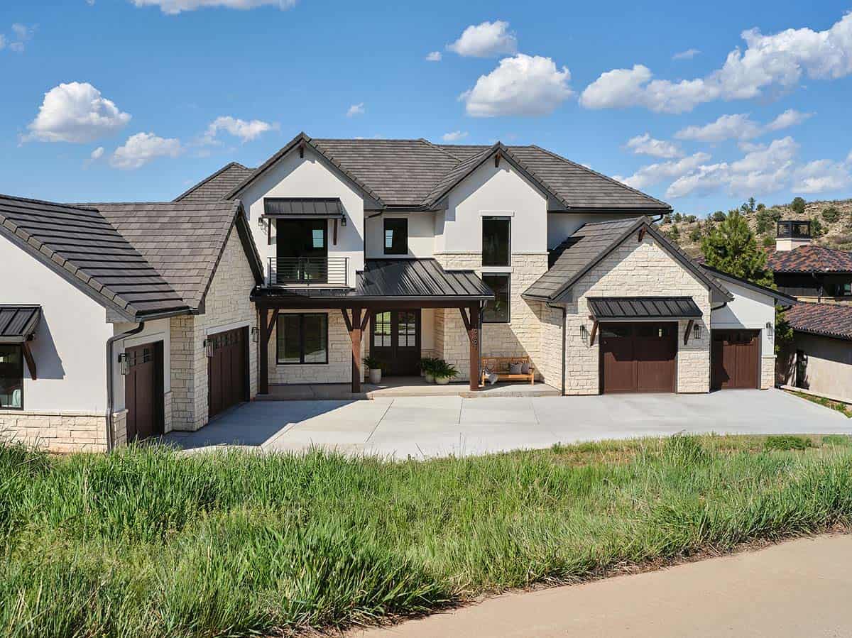 Side view of stone and stucco mountain home showing multiple garage bays and covered driveway entrance