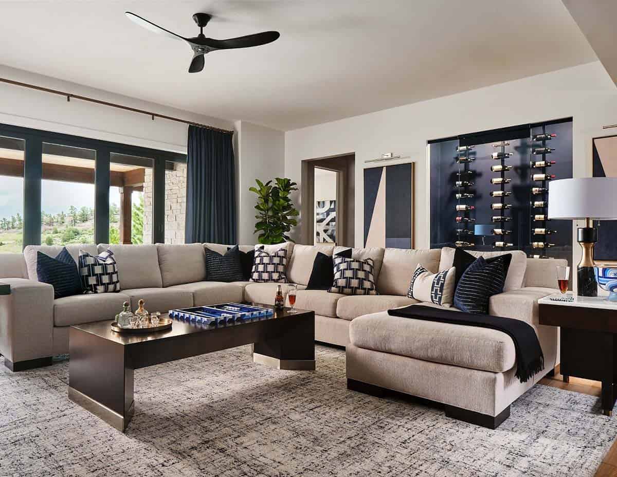 Living room with large beige sectional sofa, navy pillows, dark wood coffee table, and built-in wine display
